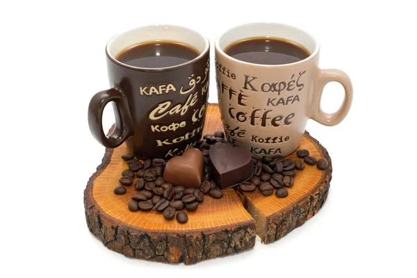 Twee kopjes koffie, chocolade harten en koffie bonen op de stomp geïsoleerd — Stockfoto