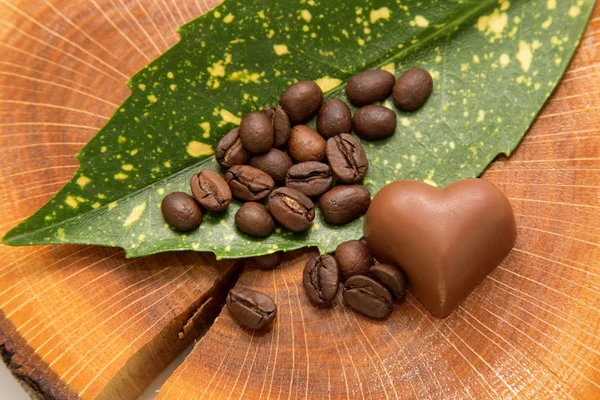 Coffee beans on the leaf with chocolate heart — Stock Photo, Image
