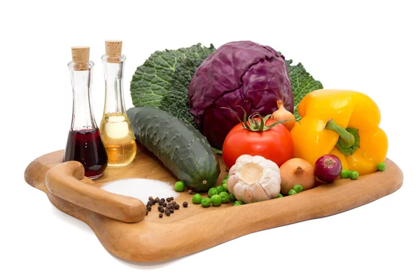 Cucumber, pepper, onion, garlic, cabbage, tomato, vinegar, oil, salt  and pepper on a wooden board Stock Image