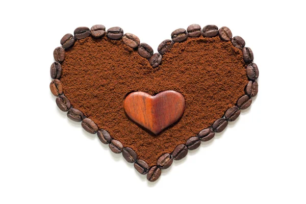 Heart made of ground coffee surrounded by coffee beans with a wooden heart in the middle isolated — Stock Photo, Image