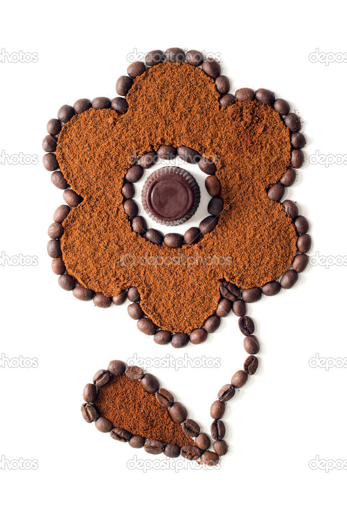 Flower made of coffee beans and ground coffee with chocolate candy in the middle isolated