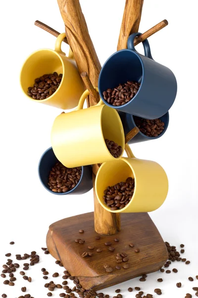 Geel en blauw kopjes koffie gevuld met koffiebonen op een houten tribune voor cups — Stockfoto