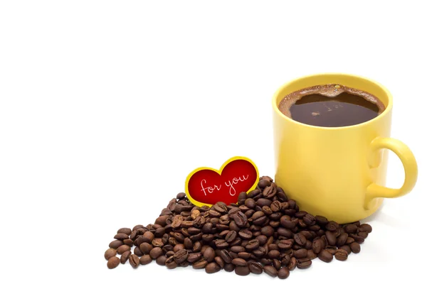 Gele kopje koffie met koffiebonen en kleine rode hart geïsoleerd — Stockfoto