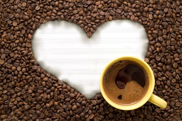 White paper in heart shape with yellow cup of coffee — Stock Photo, Image