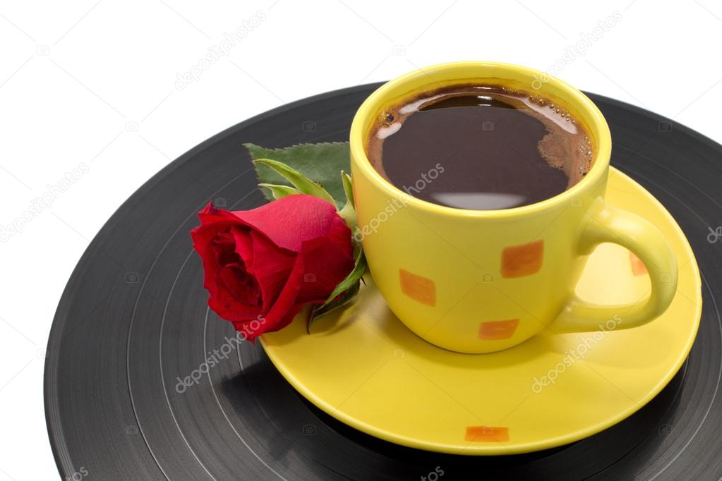 Cup of coffee with beautiful red rose on black record