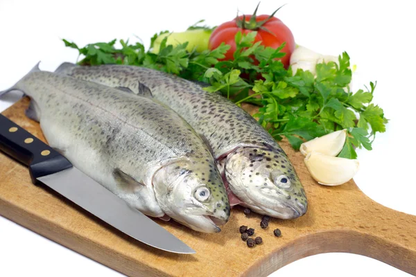 Fresh trout on wooden board with parsley, garlic, tomato, pepper and knife — Stock Photo, Image