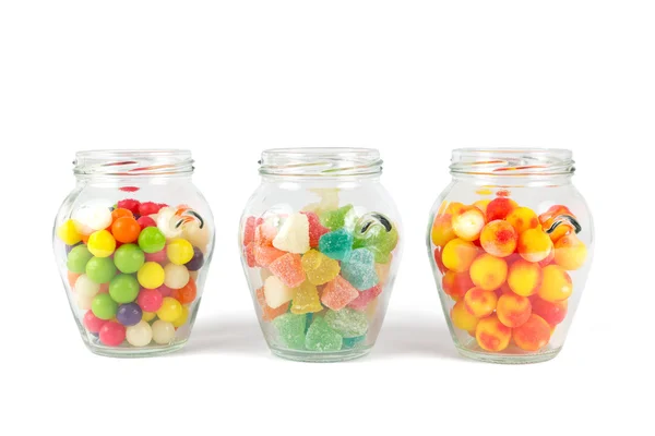 Pots en verre remplis de différents bonbons colorés isolés sur blanc — Photo