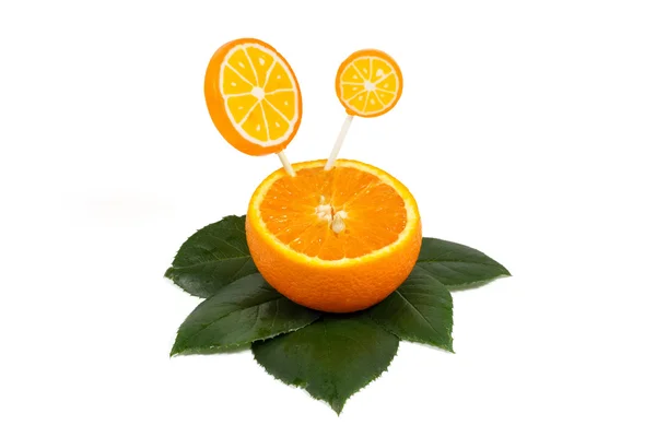 Fruit orange tranché avec sucettes orange sur feuilles vertes isolées sur blanc — Photo