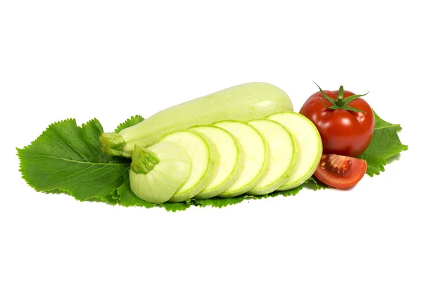 Zucchine fresche verdi chiare affettate con pomodoro su foglia di rafano isolata su bianco — Foto Stock