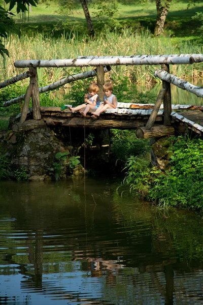 Adorable Little Twin Brothers Sitting on the Edge of Wooden Bridge and Fishing on Beautiful Lake — Stock Photo, Image