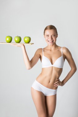 gülümseyen ve yeşil elma ahşap t üzerinde tutarak skinny genç kız