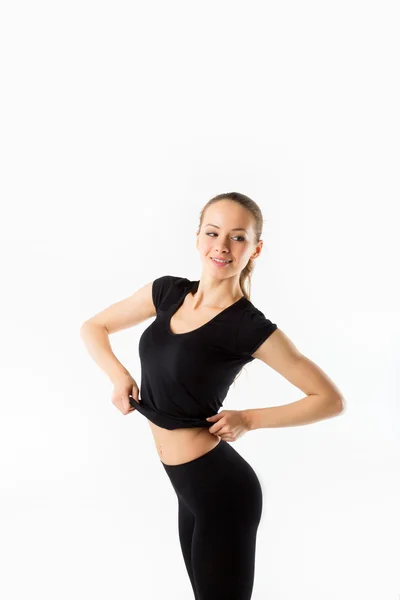 Mujer joven en forma. Sonrisas y plantea camiseta deportiva negro —  Fotos de Stock