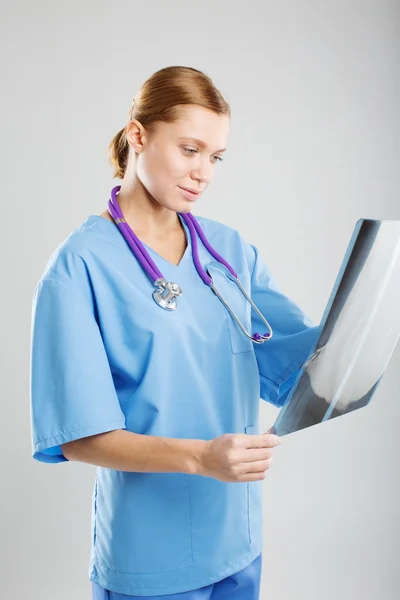 Attractive doctor or radiologist standing examining an x-ray film in a hospital as she checks on progress or makes a diagnosis — Stock Photo, Image