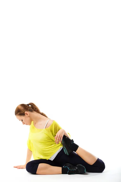 Молодая спортивная девушка делает упражнения на растяжку сидя на полу — стоковое фото