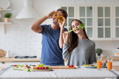 Couple is cooking on kitchen. Handsome man and attractive young woman are having fun together while making salad. Healthy lifestyle concept.