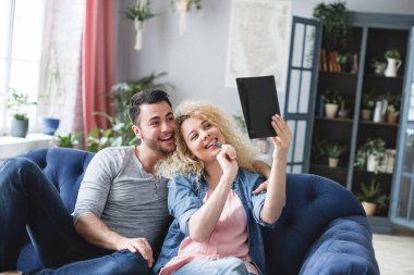 Young married couple with a notebook are counting finances on payments, time on weekends at home.