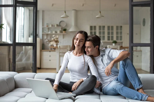 Sonriente Pareja Joven Relajarse Sofá Casa Utilizando Ordenador Portátil Compras — Foto de Stock