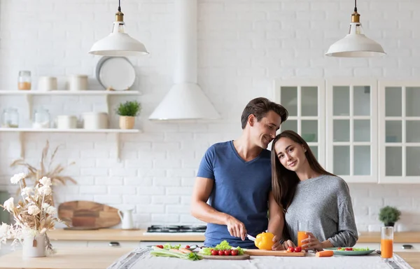 Happy young couple of vegetarians flirting in the kitchen. Healthy and wholesome food.