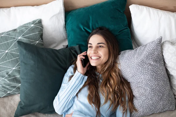 Hermosa Mujer Sonriente Hablando Teléfono Inteligente Mientras Está Acostada Cama —  Fotos de Stock