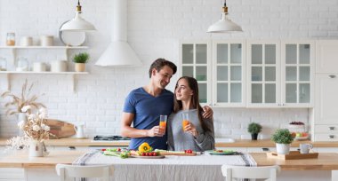 Mutfakta, masada sağlıklı ve sağlıklı bir kahvaltı hazırlayan iki vejetaryen. Evde meyve suyu içen kadın ve erkek..