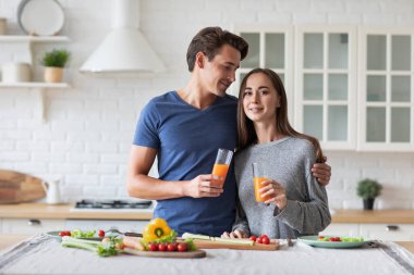 Mutfakta, masada sağlıklı ve sağlıklı bir kahvaltı hazırlayan iki vejetaryen. Evde meyve suyu içen kadın ve erkek..