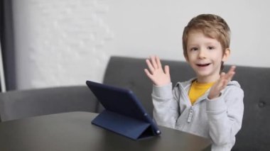 Evde dijital tabletle oynarken gülümseyen küçük mutlu çocuk. Çocuklar için boş zaman, teknoloji ve internet kavramı.