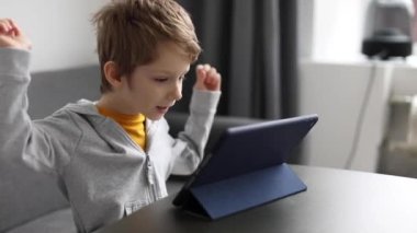 Evde dijital tabletle oynarken gülümseyen küçük mutlu çocuk. Çocuklar için boş zaman, teknoloji ve internet kavramı.