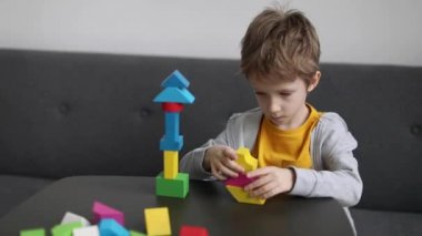 Evde renkli ahşap bloklardan bir kule inşa eden küçük bir çocuk. Çocuklar için eğitici mantıklı oyuncaklar. Çocuk gelişimi için Montessori oyunları.