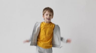 Sevimli küçük çocuk sevinçle sıçrayıp kollarını sallayarak beyaz duvar arkasında zaferi kutluyor. Evet, rüya gerçek oldu..