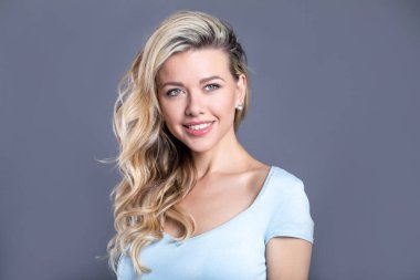 Sarışın, gri arka planda bukleli, doğal makyajlı ve temiz tenli. Portre kadını..