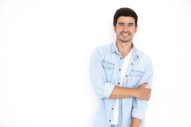 Gülümseyen, güler yüzlü, genç bir adam beyaz arka planda izole kot gömlek giyer. Pozitif duygular.