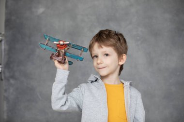 Mutlu çocuk elinde tahta uçakla oynuyor, çocuk seyahat hayalleri kuruyor. Mutluluk ve özgürlük kavramı.