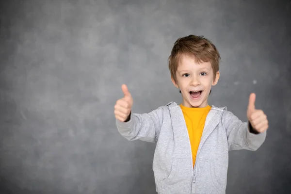 美しい幸せな男の子の肖像画は 現代の灰色の背景に親指を放棄する 子供達は好き — ストック写真