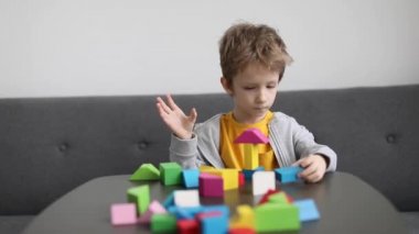 Küçük çocuk oturma odasındaki renkli ahşap bloklardan ev inşa ediyor. Yavaş çekim görüntüleri.