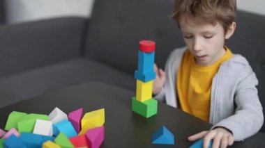 Küçük çocuk renkli tahta bloklardan ev inşa ediyor, çocuk gelişimi için montessori oyunları oynuyor. Çocukların tahta oyuncağı..