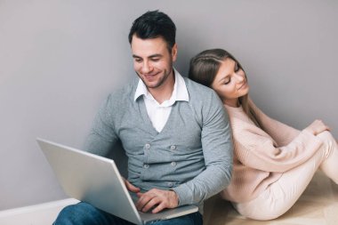 Dizüstü bilgisayarı olan çift, evde yerde oturuyor..