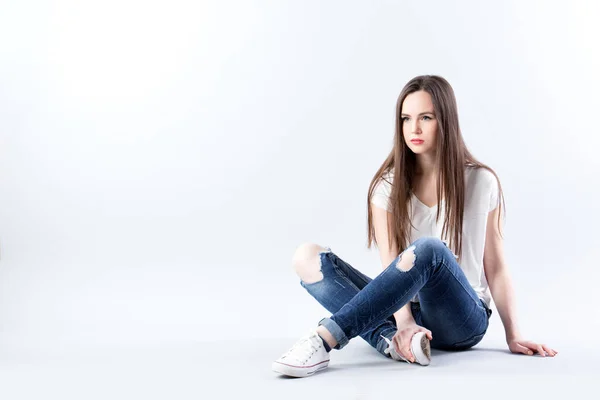 Mulher Bonita Uma Camiseta Branca Jeans Senta Chão Estúdio Isolado — Fotografia de Stock