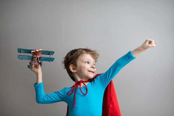 穿着红色斗篷的超级英雄小男孩玩飞机 快乐的微笑的孩子 动机和旅行概念 — 图库照片