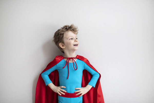 Little boy superhero with red cape. Happy smiling child. Success, motivation concept.