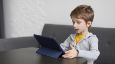 Küçük çocuk dijital tablette bir oyun oynuyor. Modern çocuk ve eğitim teknolojileri.