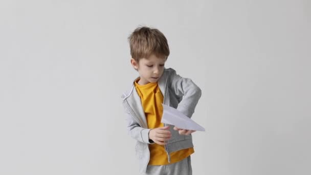 Schattig Jongetje Met Een Papieren Vliegtuigje Speelt Tegen Een Witte — Stockvideo