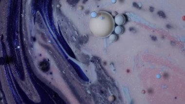 Renkli boya damlaları suya karışıyor. Mürekkep suyun altında dönüyor. Renkli kabarcıkların soyut arkaplanı.