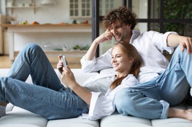 Milenyum çifti kanepeye oturup dijital tablet kullanarak rahatlıyor. Ev hayatının tadını çıkarıyorum..