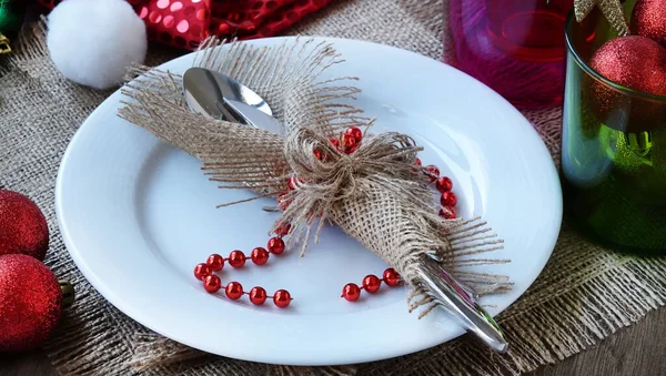 クリスマスの装飾が施された白い皿の上に 純ナプキンに包まれたスタイリッシュなカトラリーセット — ストック写真