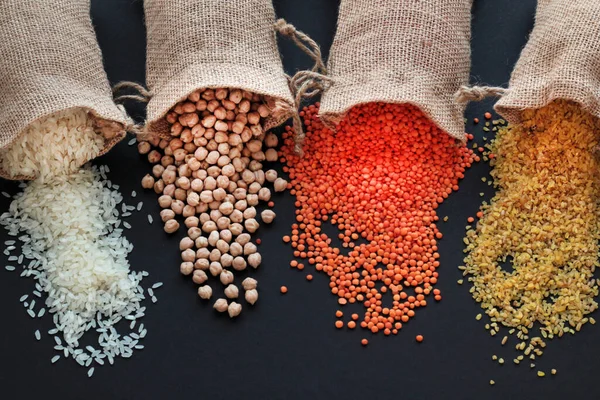 Kırmızı mercimek, nohut, beyaz pirinç ve bulgur siyah yüzeye fotokopi alanı ile dökülüyor. Hasat konsepti