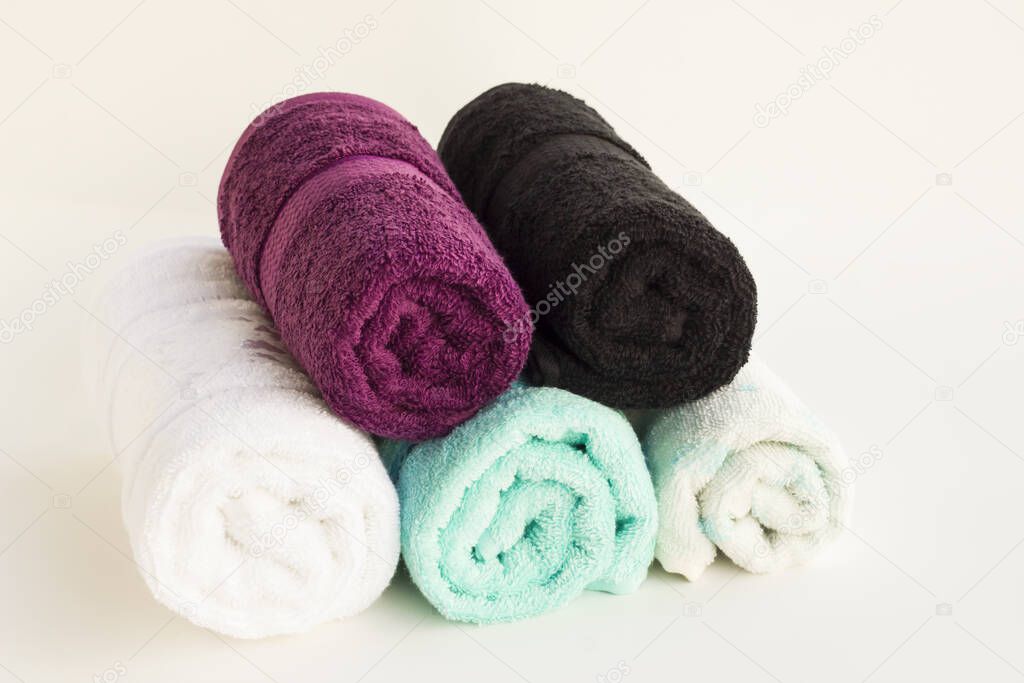 Rolled up multi color bath and face towels on white background with copy space