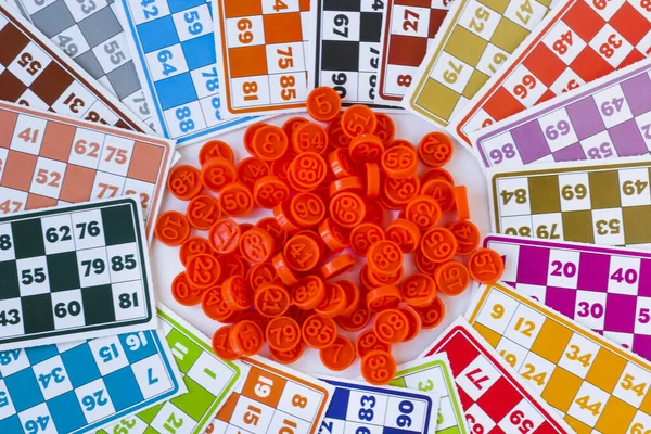 Colorful bingo game cards and plastic numbers on white background,above view