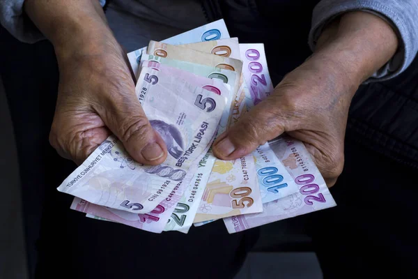 Yaşlı bir adamın elinde siyah gömleğin üzerinde Türk banknotları var. Yakın plan, emeklilik konsepti.
