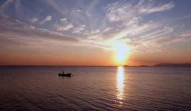 The sunset on the skyline over the sea with tiny shadow fishing boat  