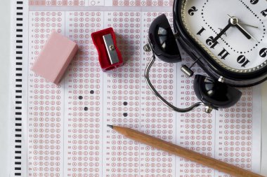 Alarm saati, dolgulu sınav kağıdında tahta kalem ve kauçuk, eğitim sınavının kavramsal görüntüsü.
